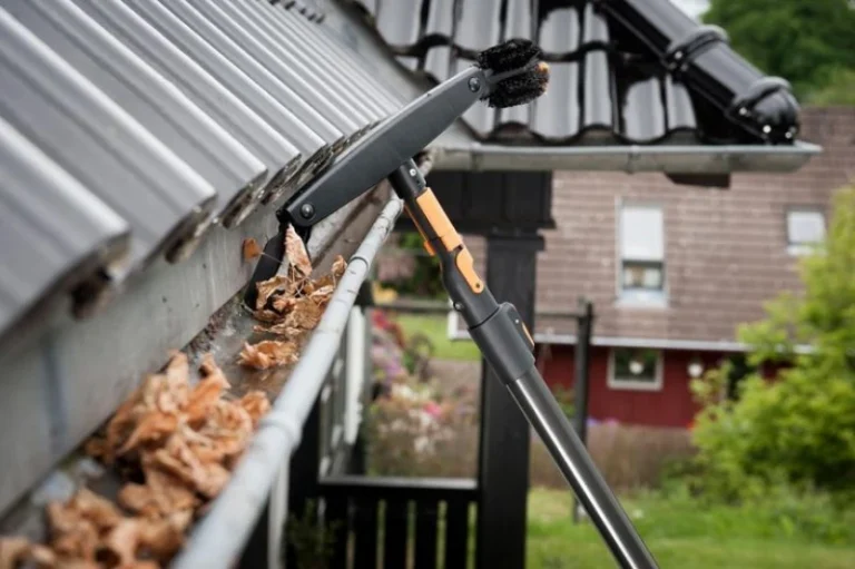 A gutter cleaning tool removing leaves from a roof gutter, showcasing effective home maintenance and outdoor cleaning solutions.